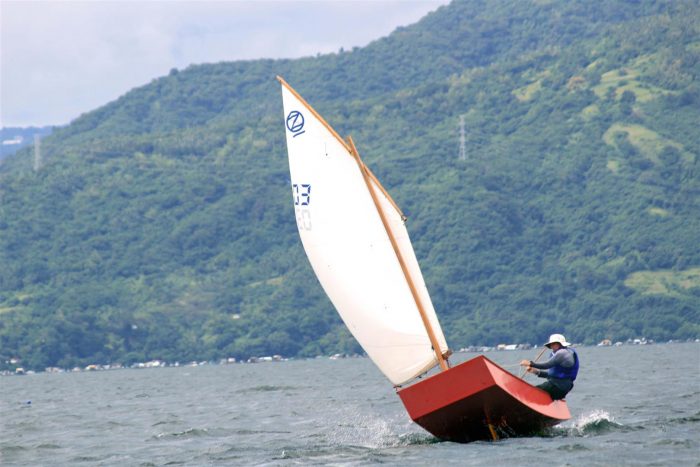 Oz Goose club racing dinghy jumping over a wave